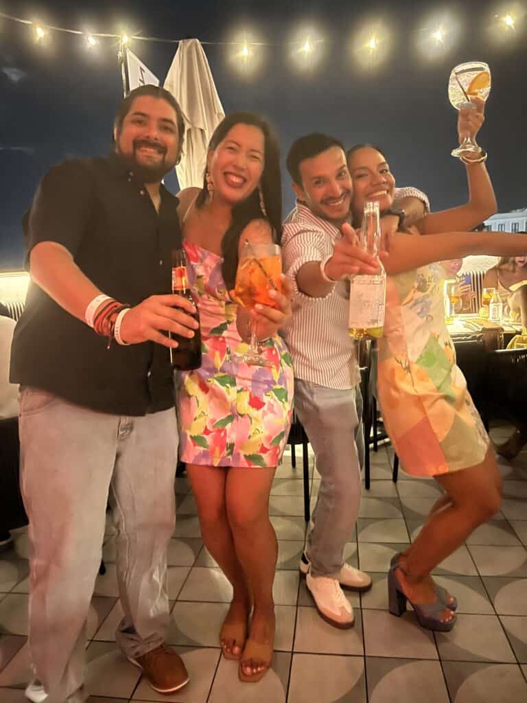 Grupo de cuatro amigos celebrando con bebidas en terraza nocturna en Buenaventura, Panamá