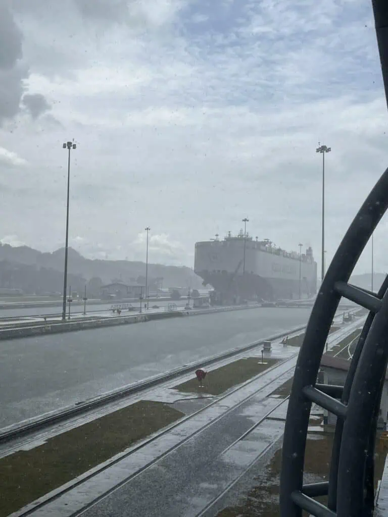 Barco de carga cruzando las Esclusas de Miraflores en el Canal de Panamá bajo lluvia tropical