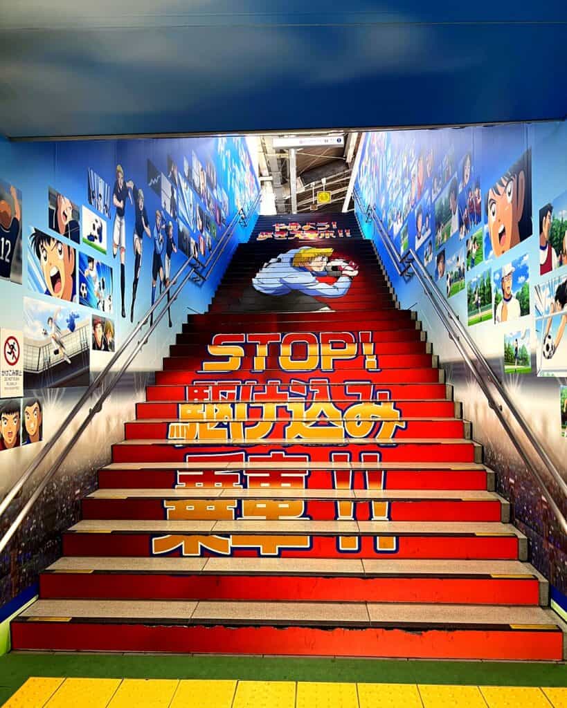 Escaleras rojas decoradas con el logo Stop de Captain Tsubasa en la estación Yotsugi, Tokio